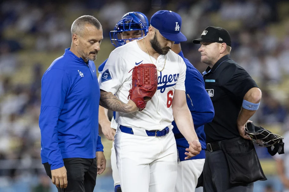 Dodgers closer Tanner Scott walks off the field with trainer Greg Barajas after sustaining an injury against the Twins.