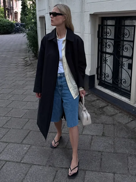 An image of @ lindatol_ wearing denim shorts trousers, one of the best anti-jeans summer trouser trends, with a tank top and scarf belt.