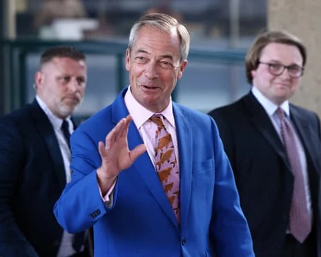 Nigel Farage smiles as he leads Reform UK headquarters after announcing his resignation as an MP. H