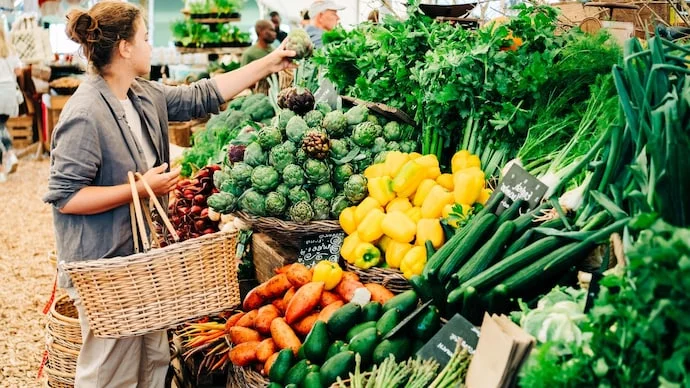 Woman choosing fruits and vegetables at farmers market.