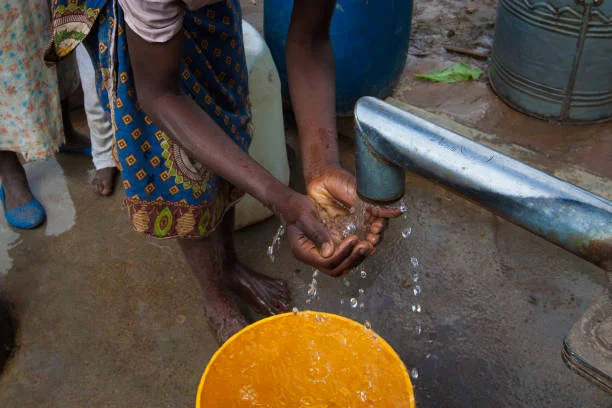a girl washing her hands at a borehole in southern malawi. - water drought stock pictures, royalty-free photos & images