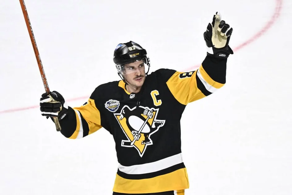 Sidney Crosby salutes the crowd while wearing a black Pittsburgh Penguins jersey.