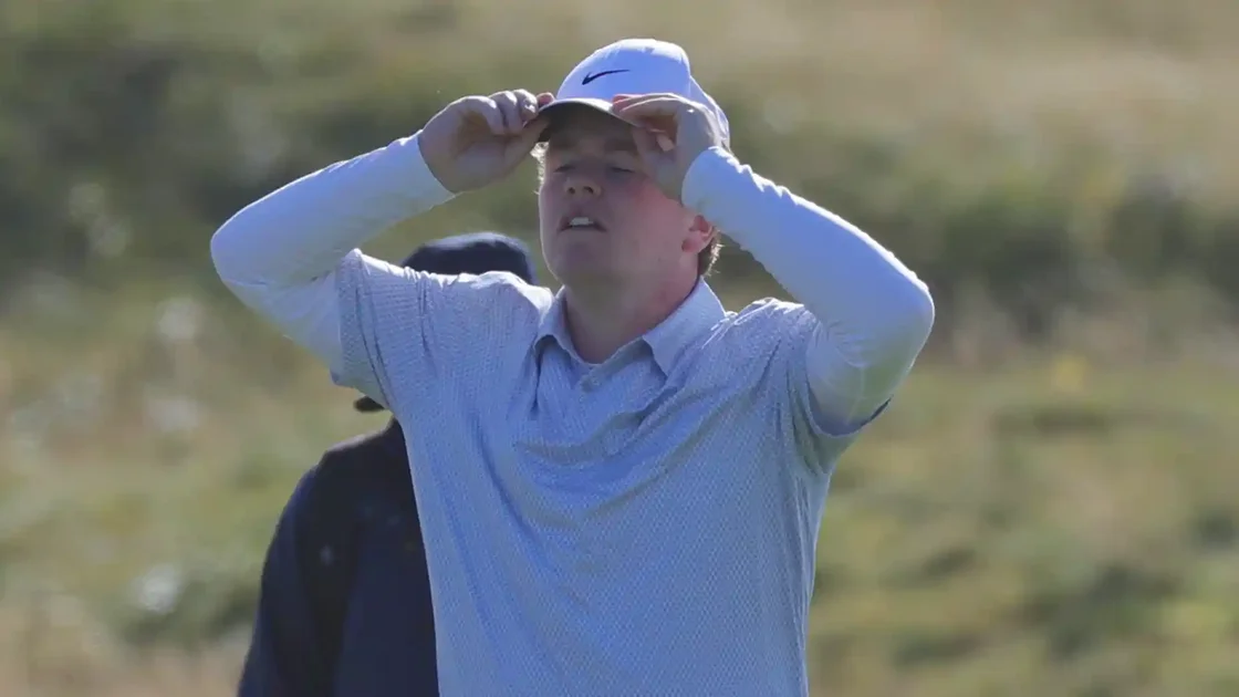 Robert MacIntyre grasps golf hat during the 2026 Alfred Dunhill Links Championship at Carnoustie.