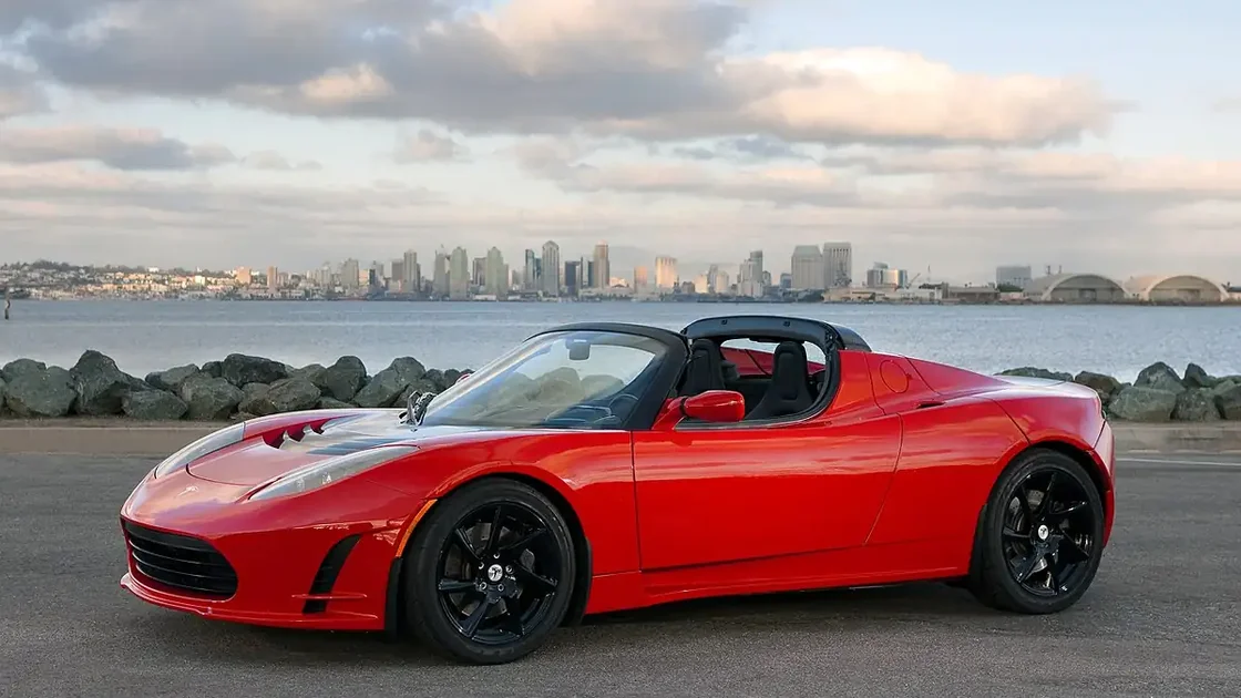 An electric sports car displayed outdoors on open pavement under direct daylight.